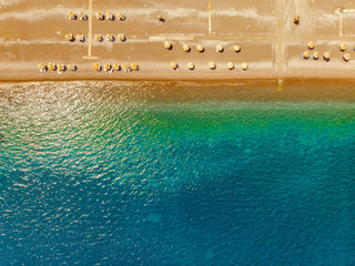Top view of sandy shore, umbrellas, azure sea /