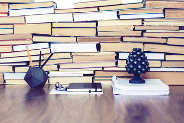 Stack of old book on wooden table, notebook, smartphone, stationery and paperweight. Education writer concept background.