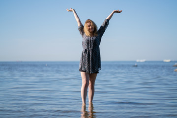 Obraz premium Attractive plus size woman in chiffon dress enjoys the shiny water in the blue sea