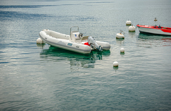 Inflatable and usual motor boats are moored to buoys