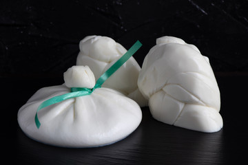 Different types of cheese on a black stone plate on a dark background