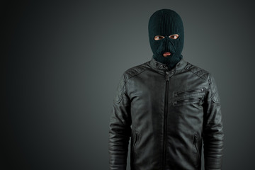 Robber, thug in a balaclava on a black background. Robbery, hacker, crime, theft. Copy space.