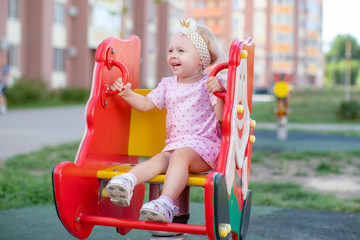 Fototapeta na wymiar Cute happy toddler girl at children's slide on a playground or kindergarten