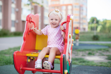 Cute happy toddler girl at children's slide on a playground or kindergarten