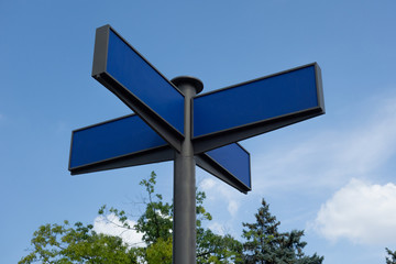 Direction road sign mock up. Real arrow form tables with blank empty space to add any text or symbols. Four destinations plates on pole to direct way or route on blue sky background