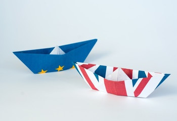 rust crack paper ships from the flags of the European Union and the UK on a blue background, concept of Brexit