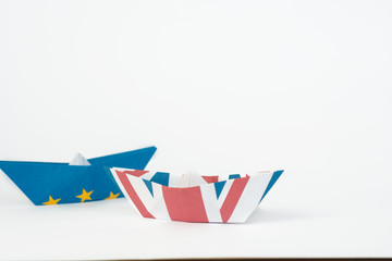 rust crack paper ships from the flags of the European Union and the UK on a blue background, concept of Brexit