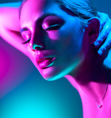 Fashion model woman in colorful bright neon lights posing in studio. Portrait of beautiful girl in UV. Art design colorful makeup