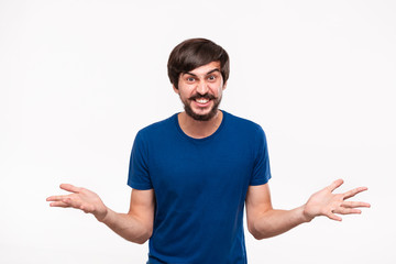 Good looking brunet man in a blue shirt with beard and mostaches shouting shrugging his shoulders being surprised standing isolated over white background.