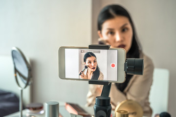 Asian woman recording a video with a phone. How to make-up tutorial online