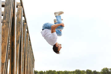 man hugging his knees and doing dives in the air, full length side view photo, treatment from fear...
