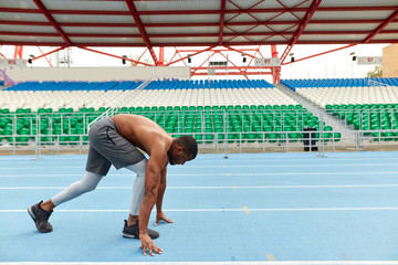 A black male runner preparing for sprint, concentration, full length side view photo. copy space.. lifestyle active life
