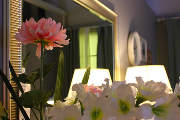 flowers on the table and a floor lamp reflected in the background mirror in the room