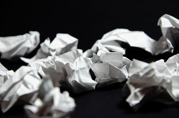 Crumpled lumps of white paper on a black background in a row top view