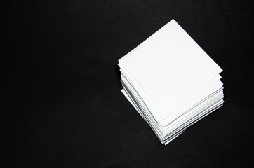 stack of white paper small squares stickers on black background