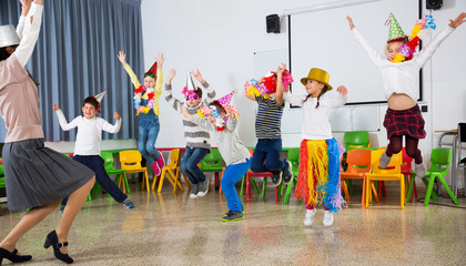Pupils and teacher in festive hats jumping