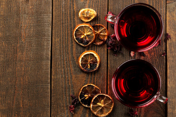 Hibiscus red tea in glass cups on a brown wooden table. a warming drink. Autumn or winter drink. top view