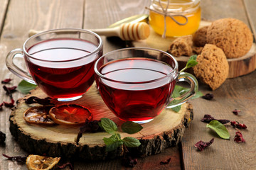 Hot red karkade tea with honey and mint. Autumn or winter soft drink. on a brown wooden table.