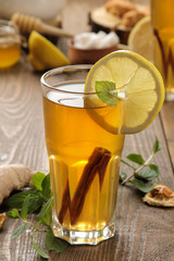 Tea with lemon and a cinnamon stick with ginger and mint in glass cups on a brown wooden table. a warming drink. Autumn or winter drink.