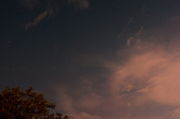 Fototapeta na wymiar Cielo stellato ricoperto da una grande nuvola rosa