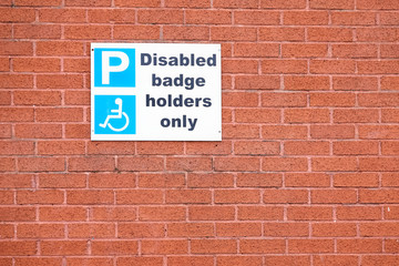 Fototapeta na wymiar Disabled blue badge holders only sign on orange brick wall
