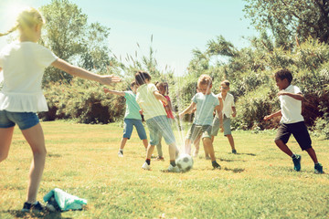 Group of happy kids are running and playing football in  park