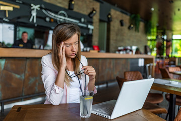 Young tired working woman. When stress erodes away at your passion. Depressed businesswoman rubbing eyes in coffe shop. Stressed woman wearing eyeglasses.