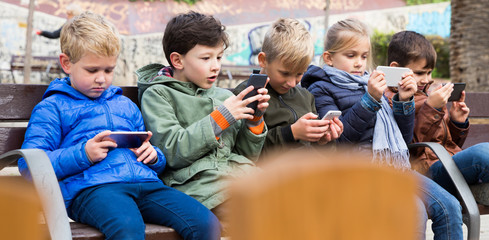 Kids playing with smartphones on bench