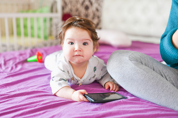 little baby with a phone. on the bed. knowledge of mobile devices. Little baby with mobile phone. Little baby in casual colorful striped clothing with mobile phone