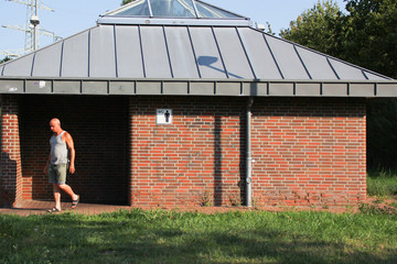 Naklejka premium a man comes out of a brown brick street public toilet with a toilet sign on the plate