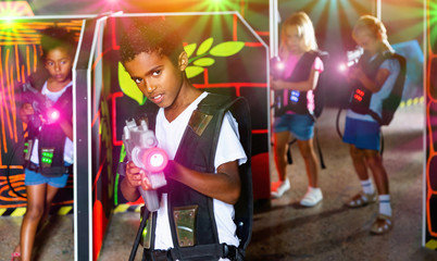 Obraz na płótnie Canvas Portrait of mulatto tweenager boy with laser gun having fun on d