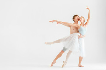 Young couple of modern ballet dancers posing over white studio background