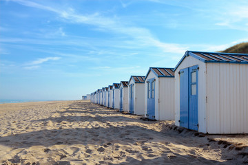 Obraz na płótnie Canvas Row of white and blue beach huts on the beach of island Texel in the Netherlands with blue sky on sunny day