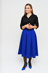 Naklejka premium Full length vertical portrait of a cute brunette middle-aged manager woman with beautiful curly hair in a business suit and blue skirt on a white background. Beauty, brightness, smile.