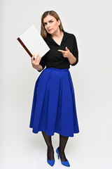 Full-length Vertical Portrait of a cute brunette middle-aged manager woman with beautiful curly hair in a business suit and blue skirt on a white background with a folder in her hands.