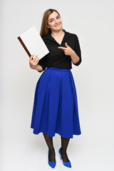 Full-length Vertical Portrait of a cute brunette middle-aged manager woman with beautiful curly hair in a business suit and blue skirt on a white background with a folder in her hands.