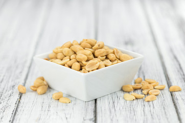Wooden table with salted and roasted peanuts (close-up shot)