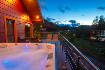 An open-air hydromassage bathtub. Hot tub on the terrace. Terrace interior of a country house....