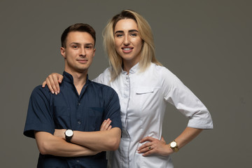 Happy Medic Workers. Portrait Of Two Doctors In White Coats Over Grey Background, Copy Space
