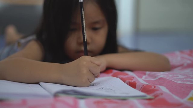 Asian child or kid holding pencil and student drawing and learning for write or paint on white paper for creative idea and art think at kindergarten classroom and nursery preschool or home on bed 4K