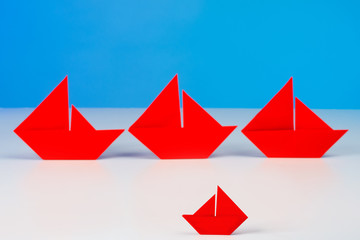 Red paper boats of different sizes. Origami. A symbol of inner freedom. Conceptual image of small and medium-sized businesses. The scarlet color symbolizes hope.