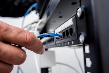 Technician connecting network cables to switches. Connecting cables in server cabinet.