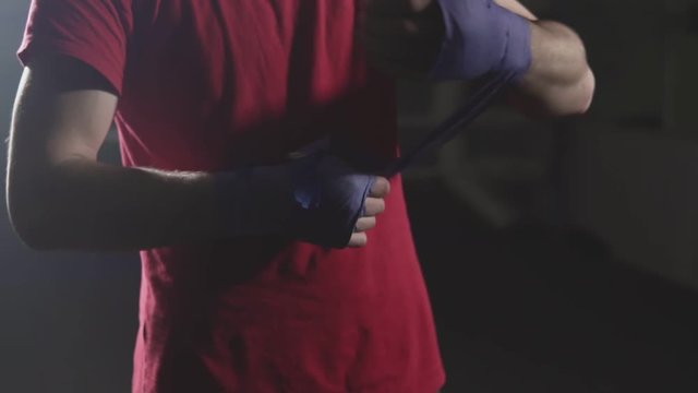Close-up of kickboxer prepare for training. Man boxer wapping hands getting ready for fight in slow motion