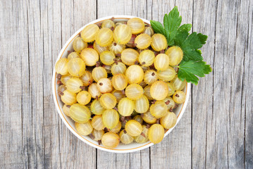 Ripe fresh gooseberry in a bowl on a wooden background
