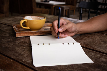 hand apn handle writen in a white notebook after drink coffee