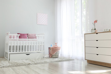 Interior of light modern baby room with crib