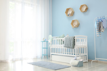 Interior of light modern baby room with crib