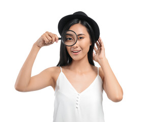 Young Asian woman with magnifying glass on white background