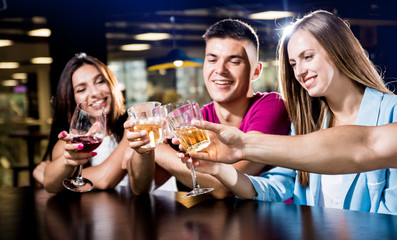 Cheerful friends in the pub. Drinking beer, wine and whisky, talking, having fun.