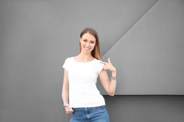Fototapeta na wymiar Woman in stylish t-shirt near grey wall